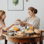 A mother and daughter share a joyful breakfast at home, highlighting family bonding.