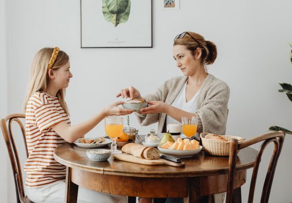 A mother and daughter share a joyful breakfast at home, highlighting family bonding.