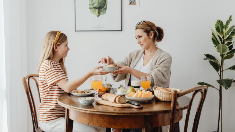 A mother and daughter share a joyful breakfast at home, highlighting family bonding.